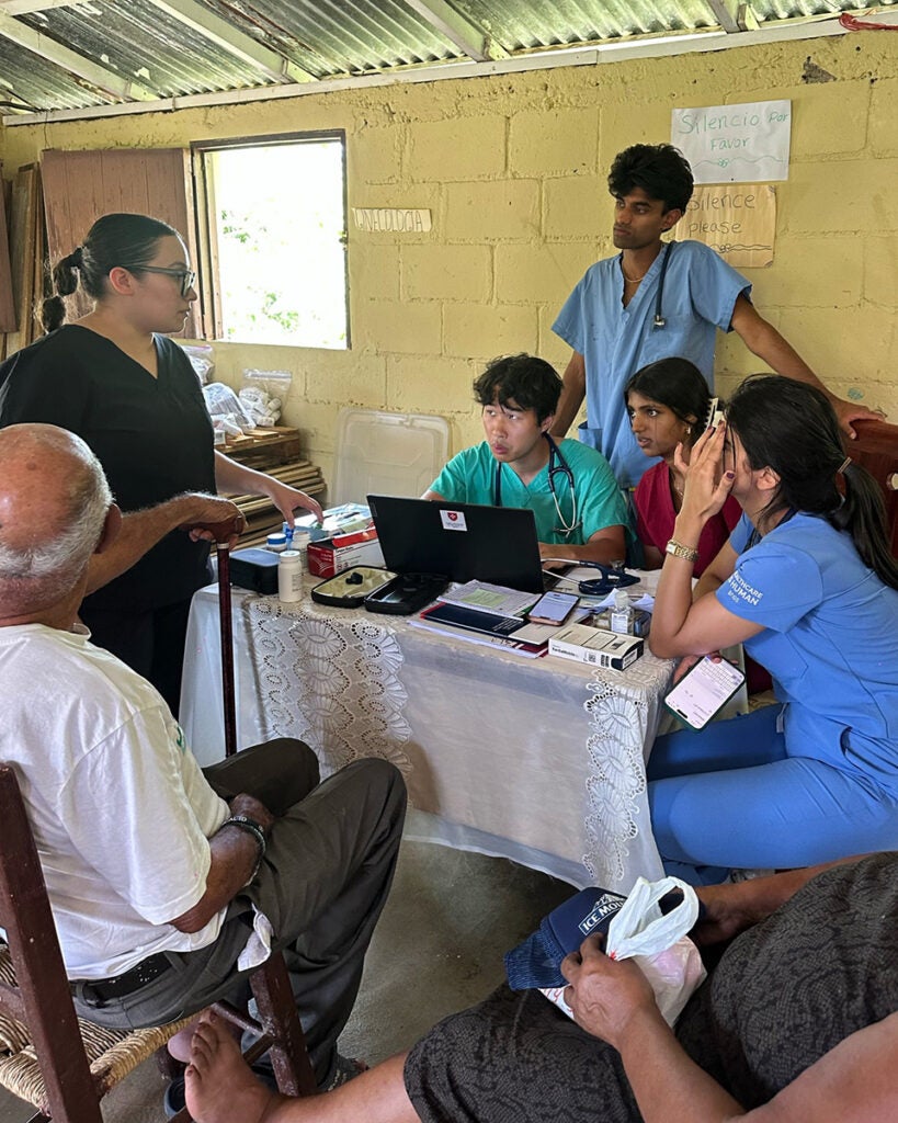 Four medical students talk with one another as patients look on