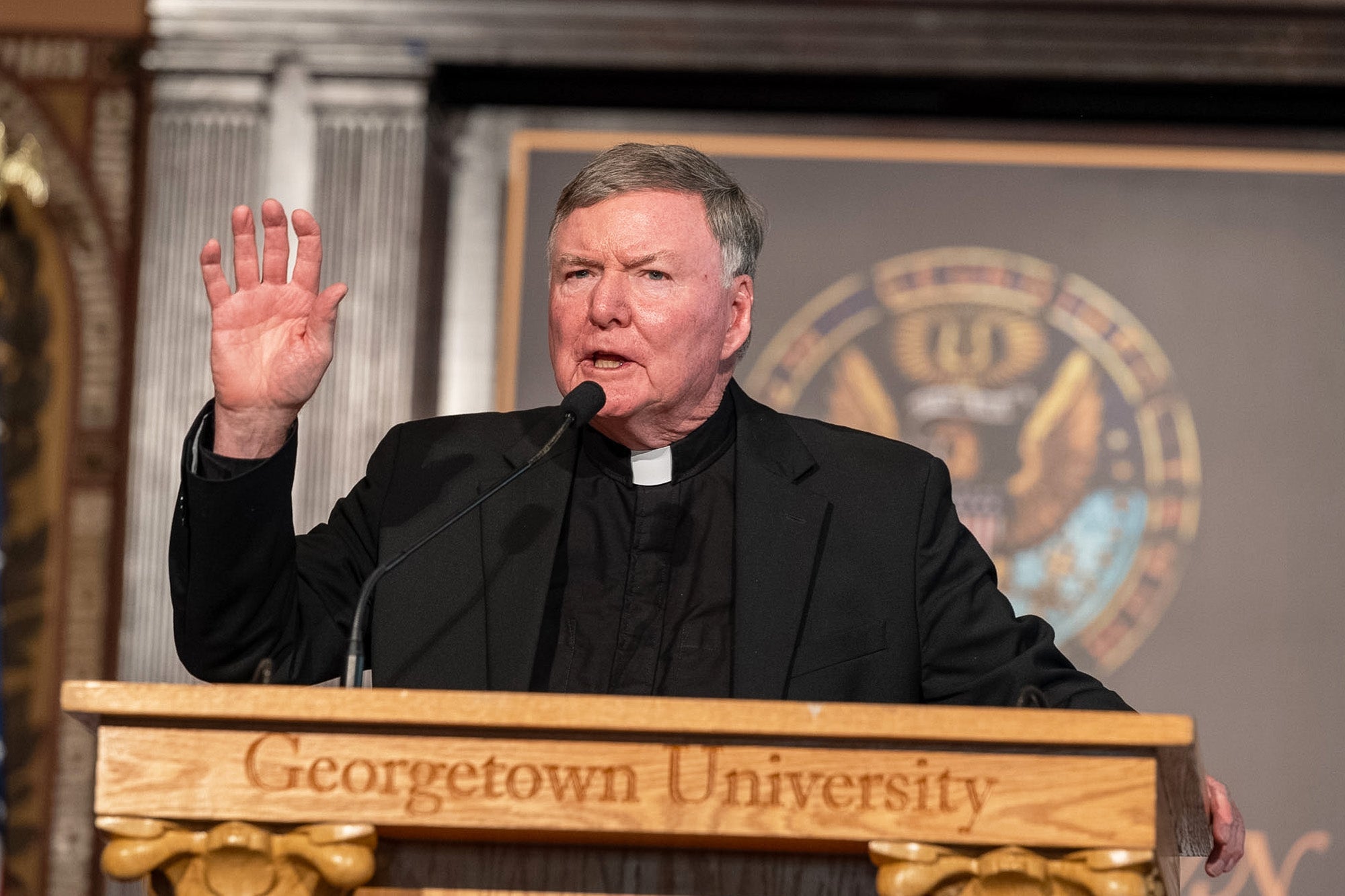Fr. Shea speaks from a podium in Gaston Hall