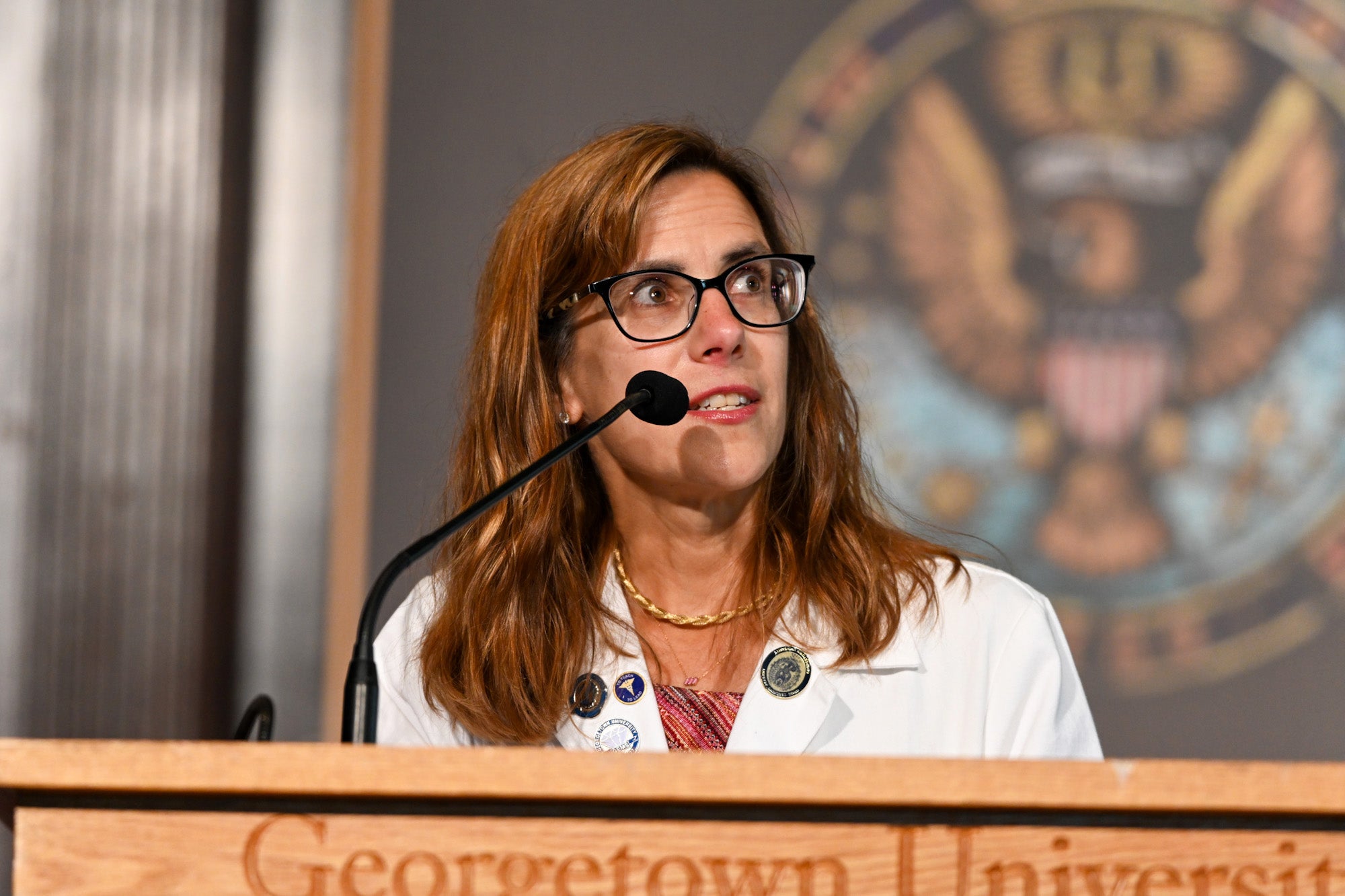 Dr. Mary Furlong speaks from a podium in Gaston Hall