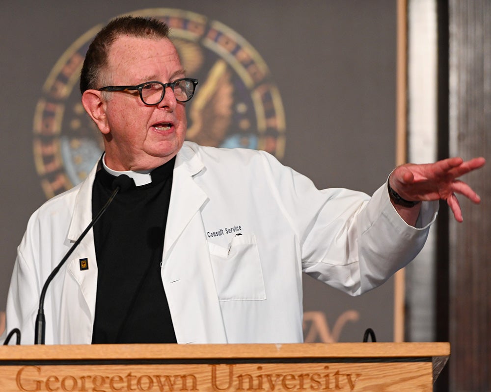 Fr. Sheehan gestures to the audience while speaking from a podium