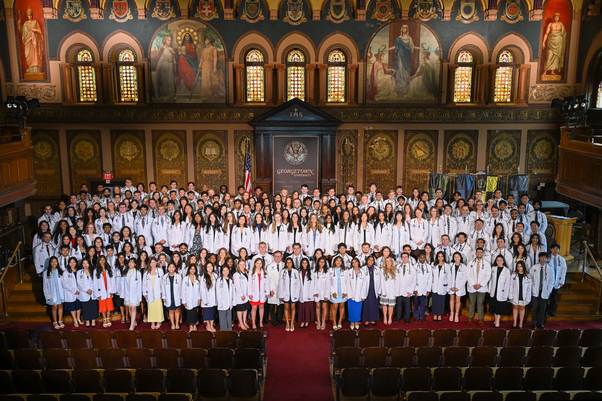 A long view of the full group of medical students standing together in Gaston Hall