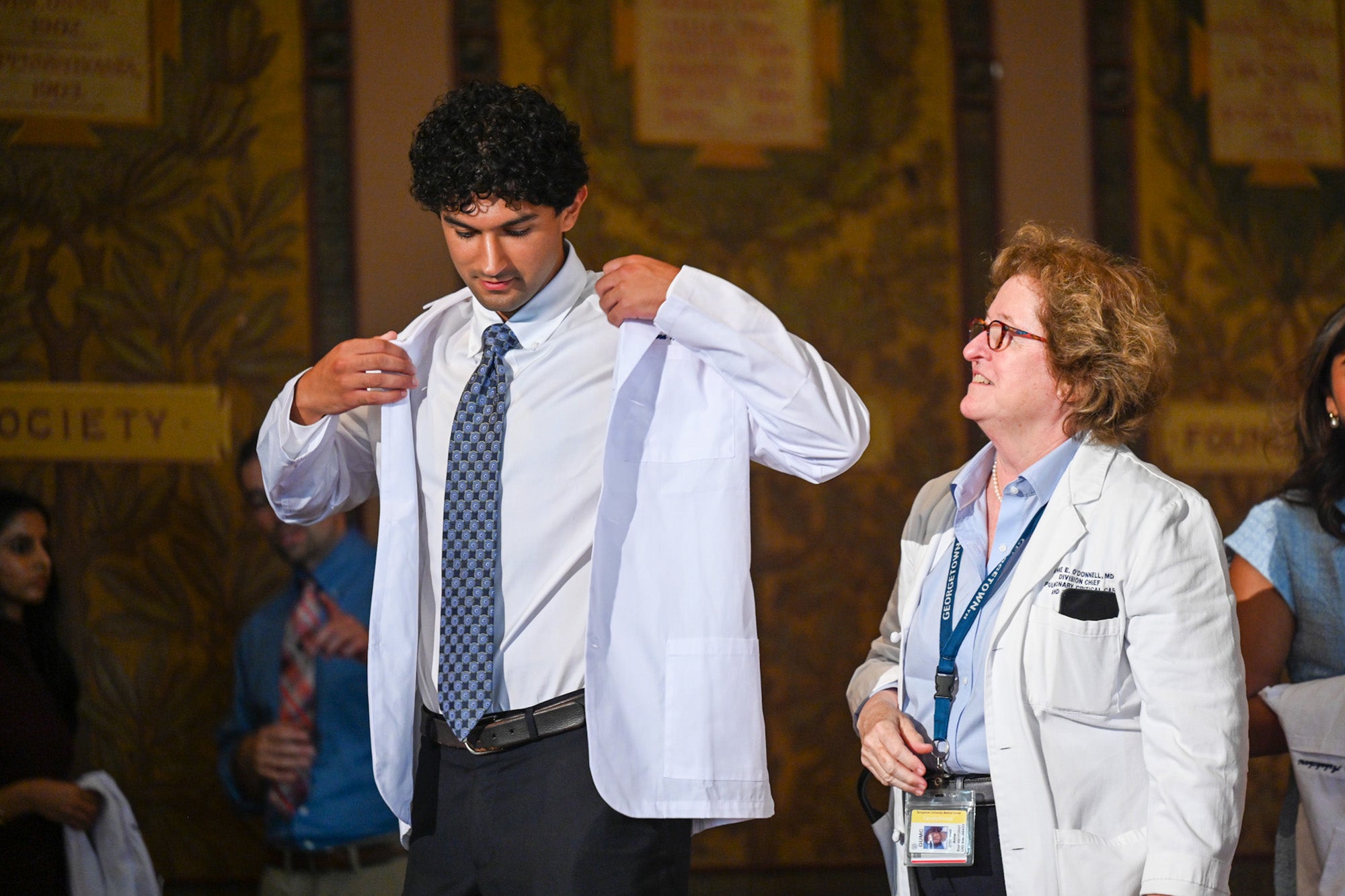 Dr. O'Donnell looks at a student as he puts on his new white coat